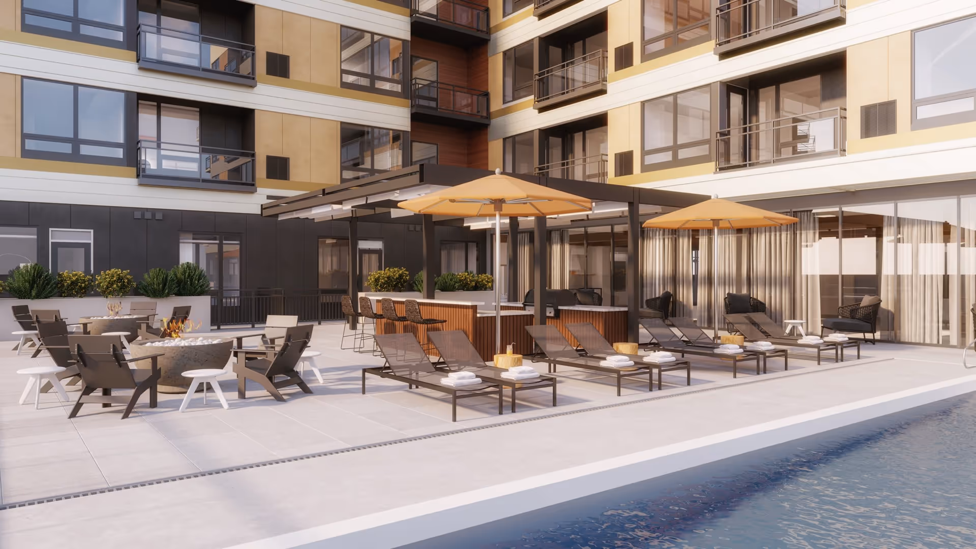 Outdoor patio area at Risor of Bloomington featuring lounge chairs with towels, umbrellas, a fire pit surrounded by chairs, and a covered bar area with stools, adjacent to a swimming pool and a multi-story building with balconies.