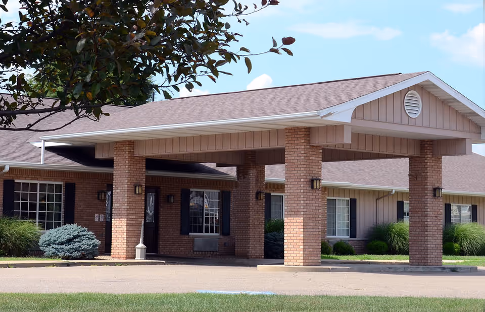 Cambridge Place Assisted Living exterior with a covered entrance supported by brick columns.