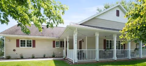 Single-story senior living facility with a wrap porch, columns, and manicured lawn.