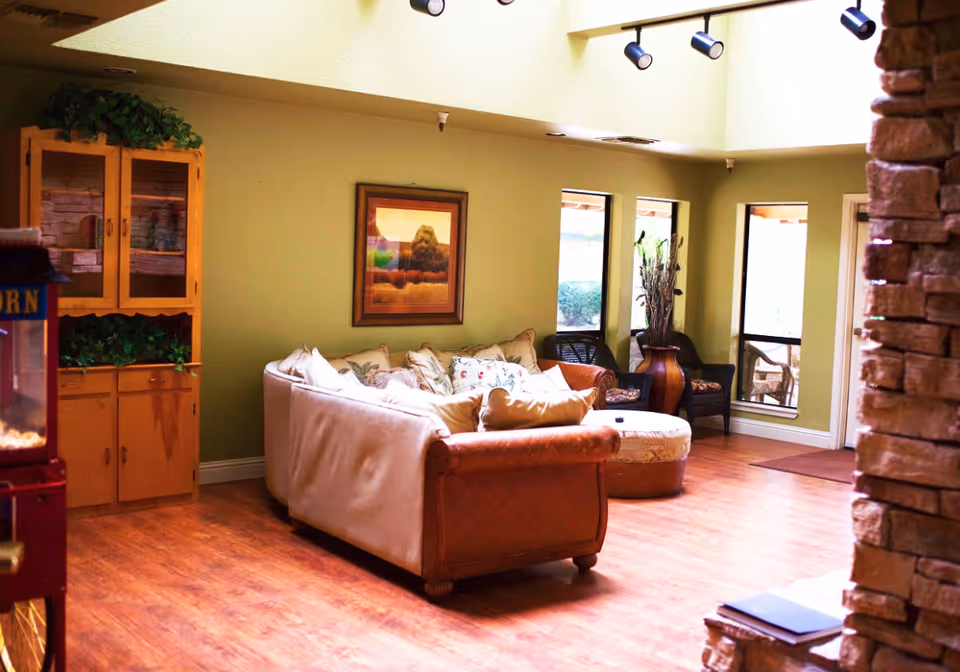 Cozy lounge with a sofa, armchairs, ottoman and wooden cabinets on a wood floor beneath skylights.