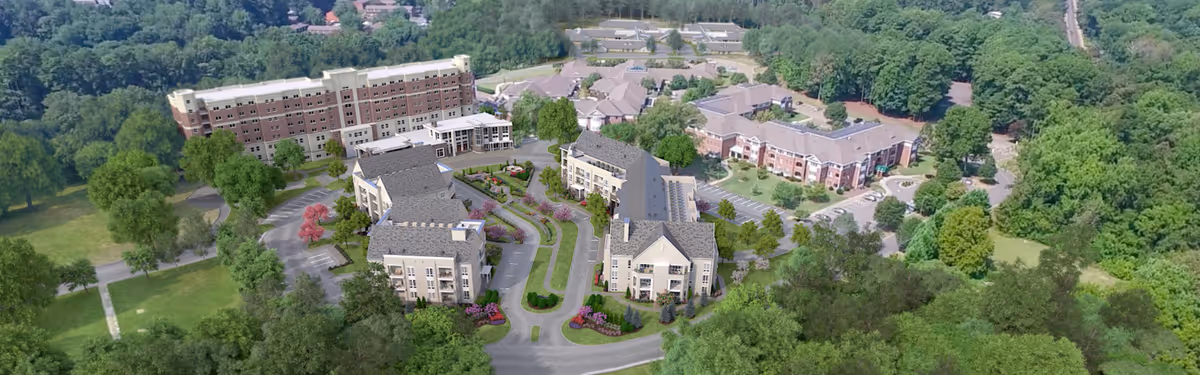 Aerial view of the Aldersgate senior living campus showing multiple residential buildings, driveways, landscaped grounds, and surrounding trees.