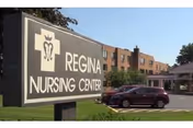 Sign reading 'REGINA NURSING CENTER' in front of a multi-story brick healthcare building with parked cars.