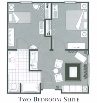 Floor plan of a two-bedroom suite showing two bedrooms, a bathroom with a bathtub, a kitchen area, and a living room with seating and a fireplace.