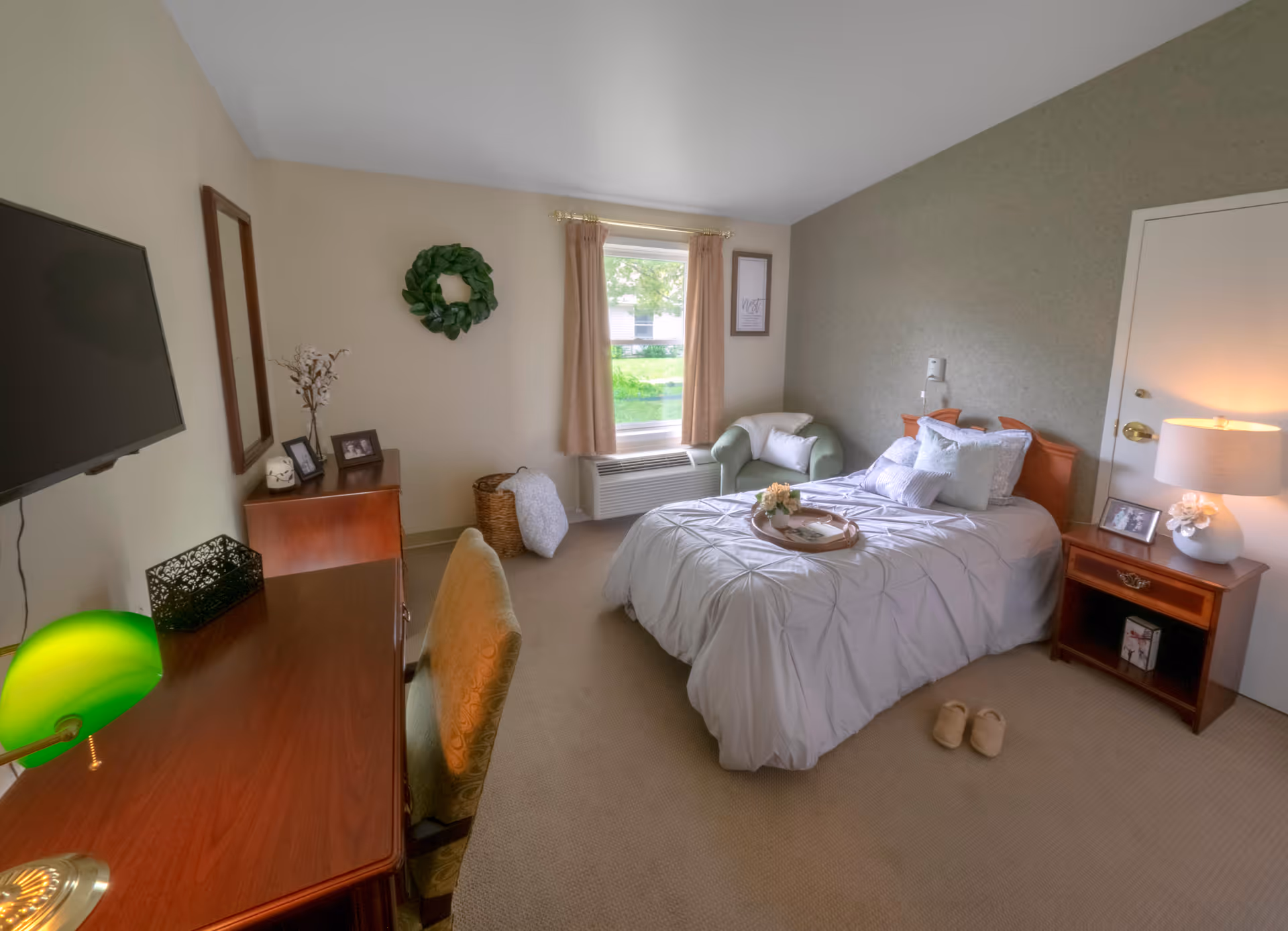 Bright furnished bedroom with a bed, nightstand, desk, armchair and window.
