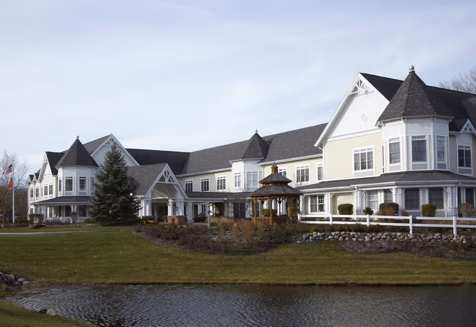 Sunrise of Gurnee senior living facility exterior with gazebo, lawn, and pond.