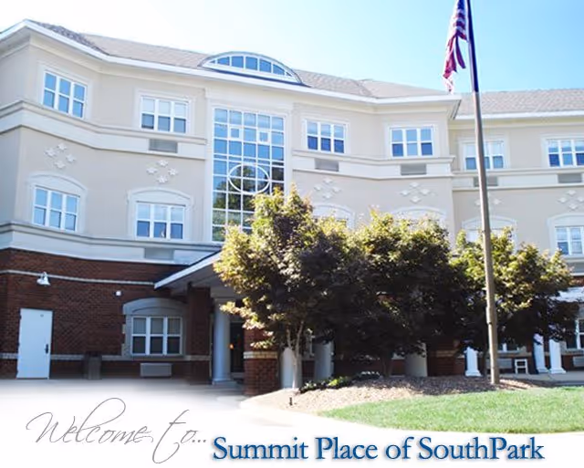 Front exterior of Summit Place of SouthPark senior living facility showing the entrance, windows, trees, and a flagpole.