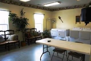 Community laundry room with washers and dryers, a folding table with chairs, and bench seating by the windows.