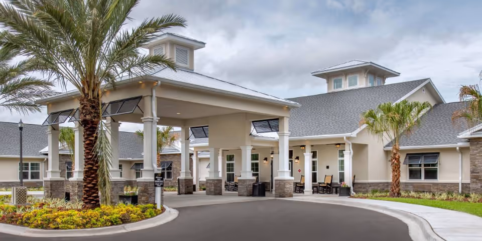 Exterior of The Addison of St. Johns with a covered entrance, columns, and palm trees.