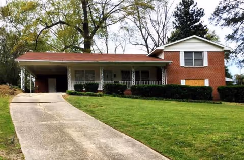 A single-story brick senior living facility with a driveway, front entrance, and green lawn.