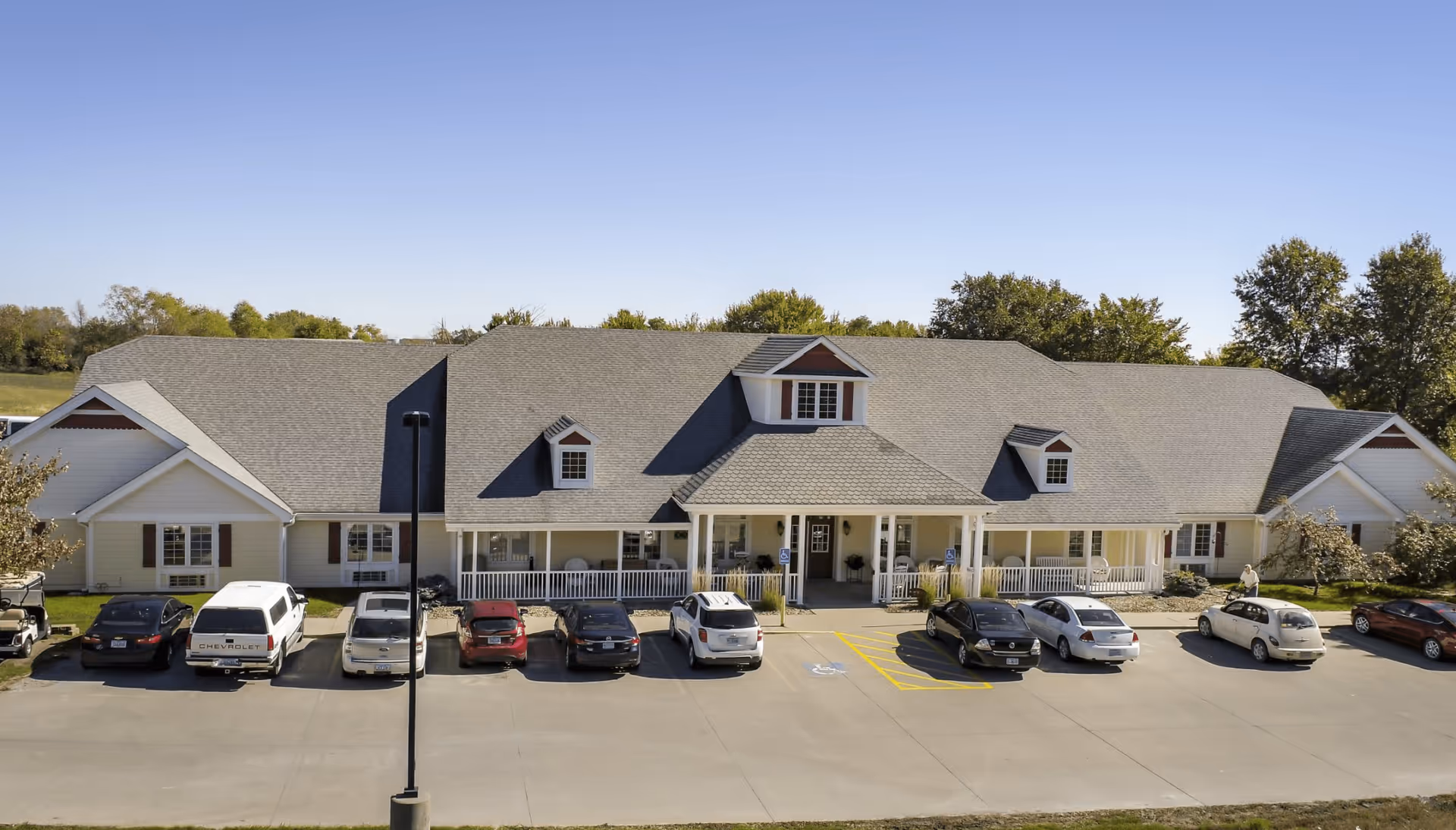 Front exterior of a single-story assisted living building with a covered porch and cars parked in front.