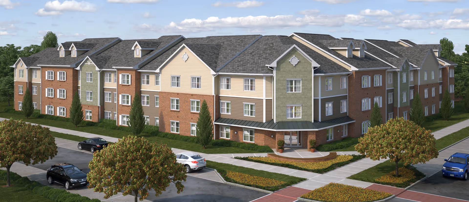 Three-story brick-and-siding senior living building with landscaped lawns, trees, sidewalks, and parked cars in front.