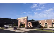 Exterior view of Westminster Village Muncie entrance with brick arches and parking.