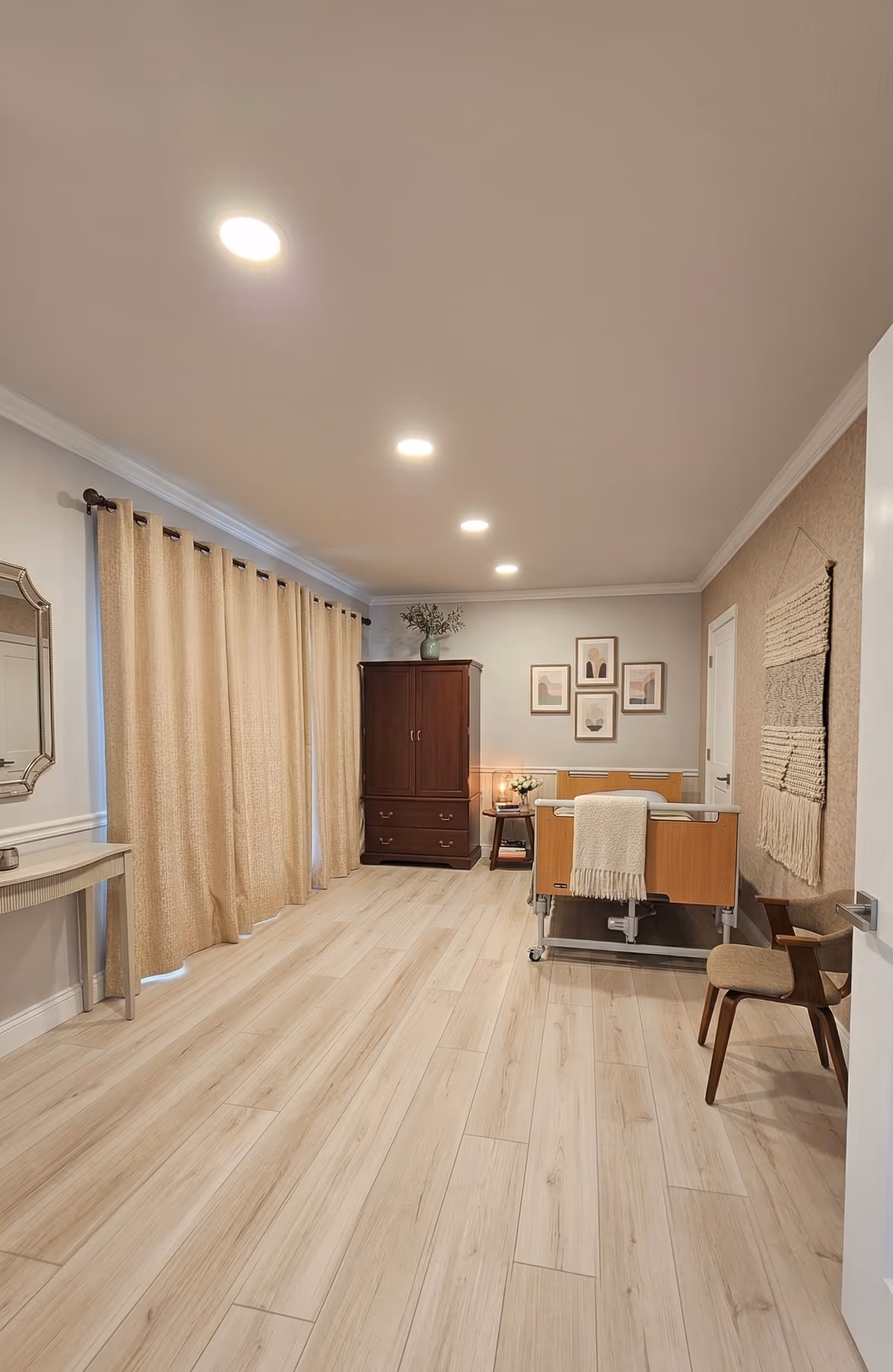 Bright patient room in a senior facility with a hospital bed, dresser, and beige curtains.