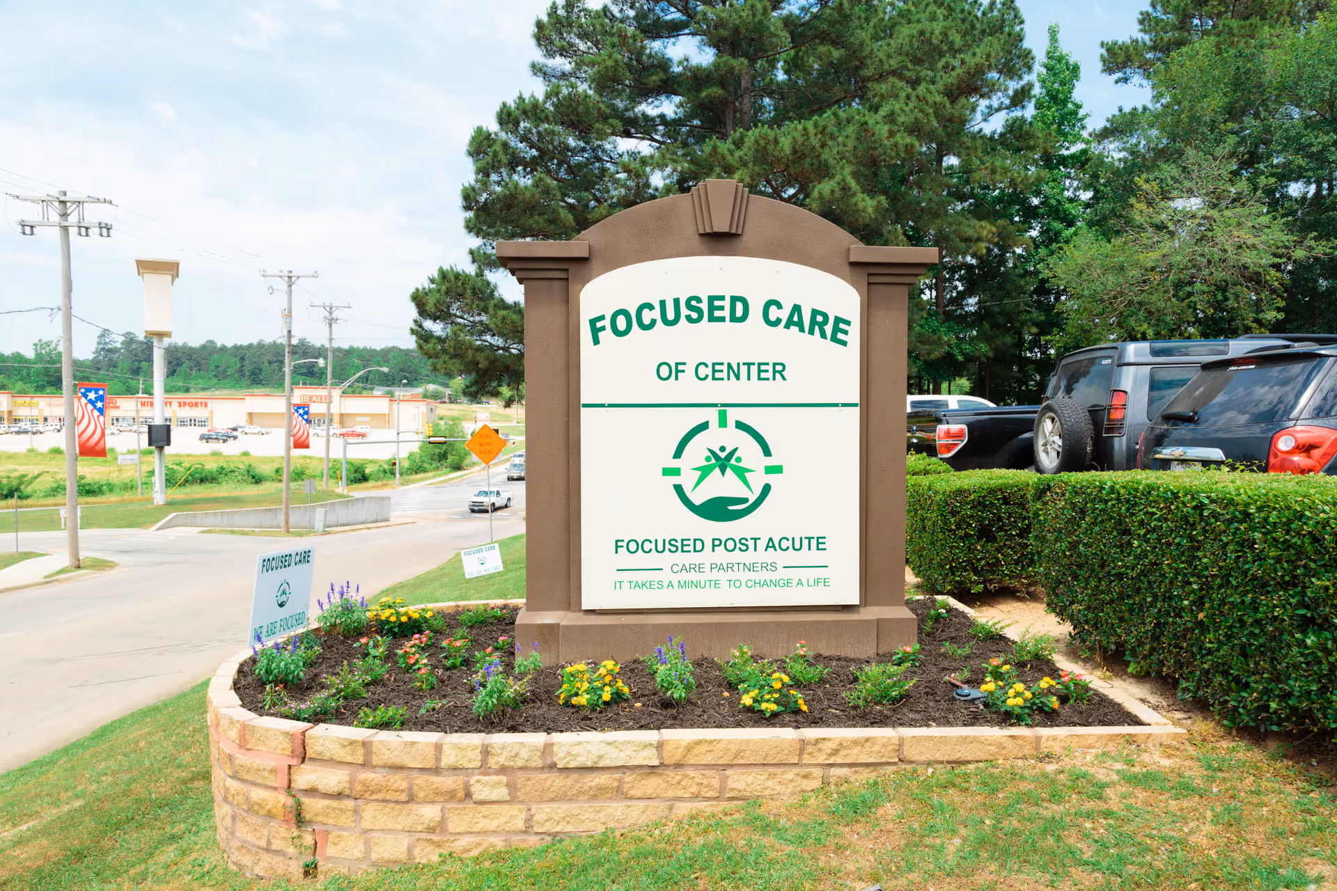 Entrance sign reading "Focused Care of Center" in a stone planter with parked cars and trees behind.
