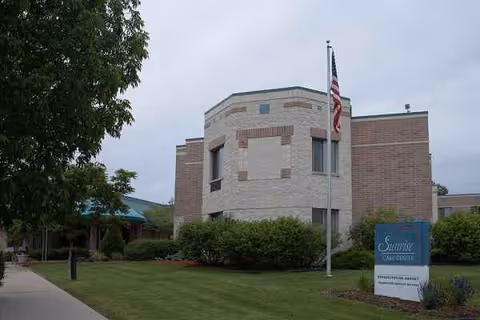 An exterior view of Sunrise Health Services building with flagpole and sign.