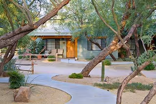 Exterior of Rustic Ranch Senior Living, curved walkway, trees, and entry door.