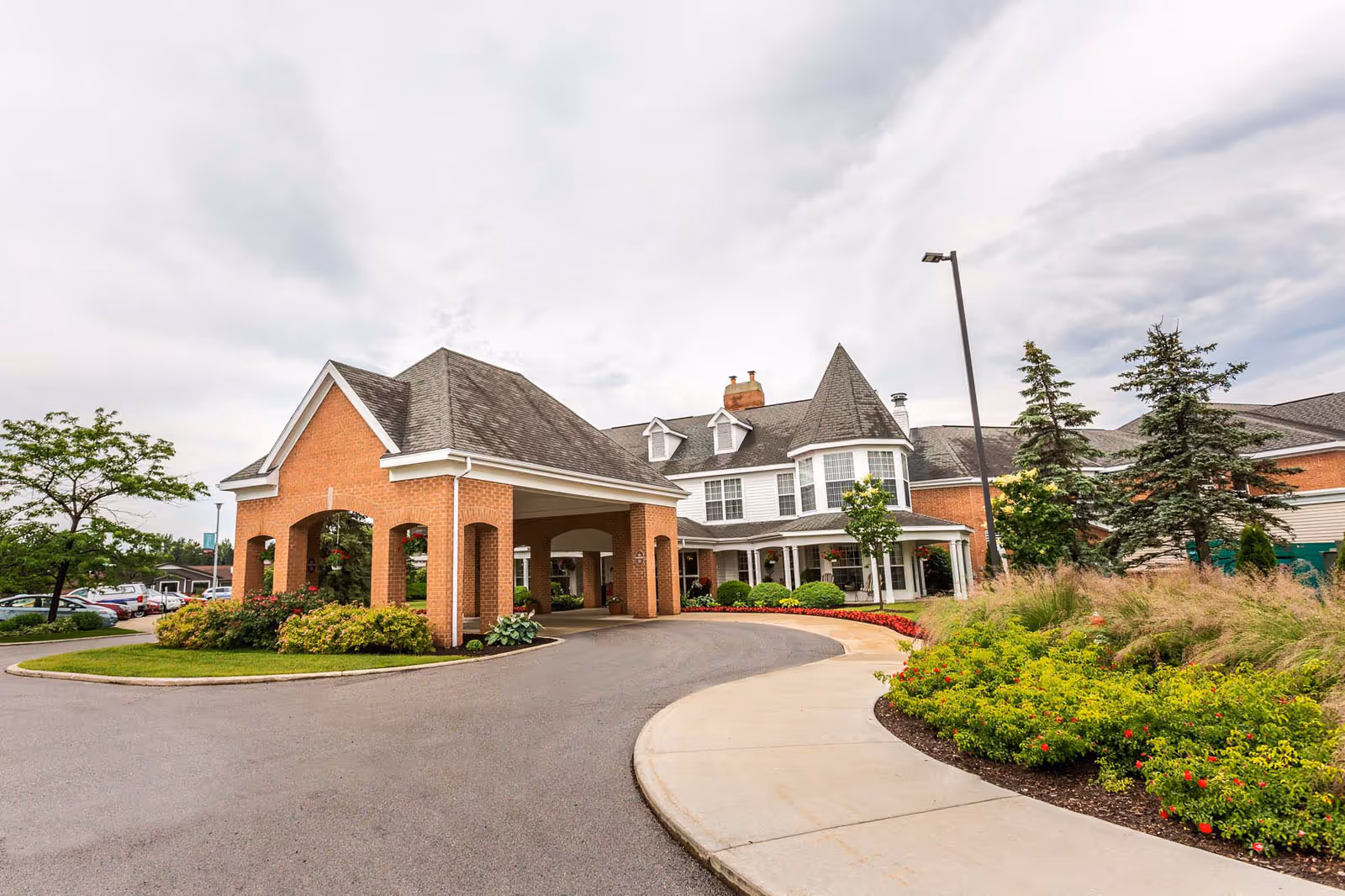 Front entrance and porte-cochère of a brick residential building with a circular driveway and landscaped gardens.