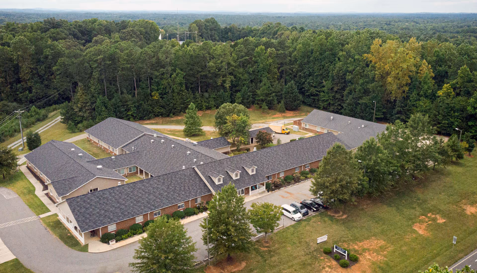 Aerial view of a senior living campus with multiple brick buildings surrounded by trees.
