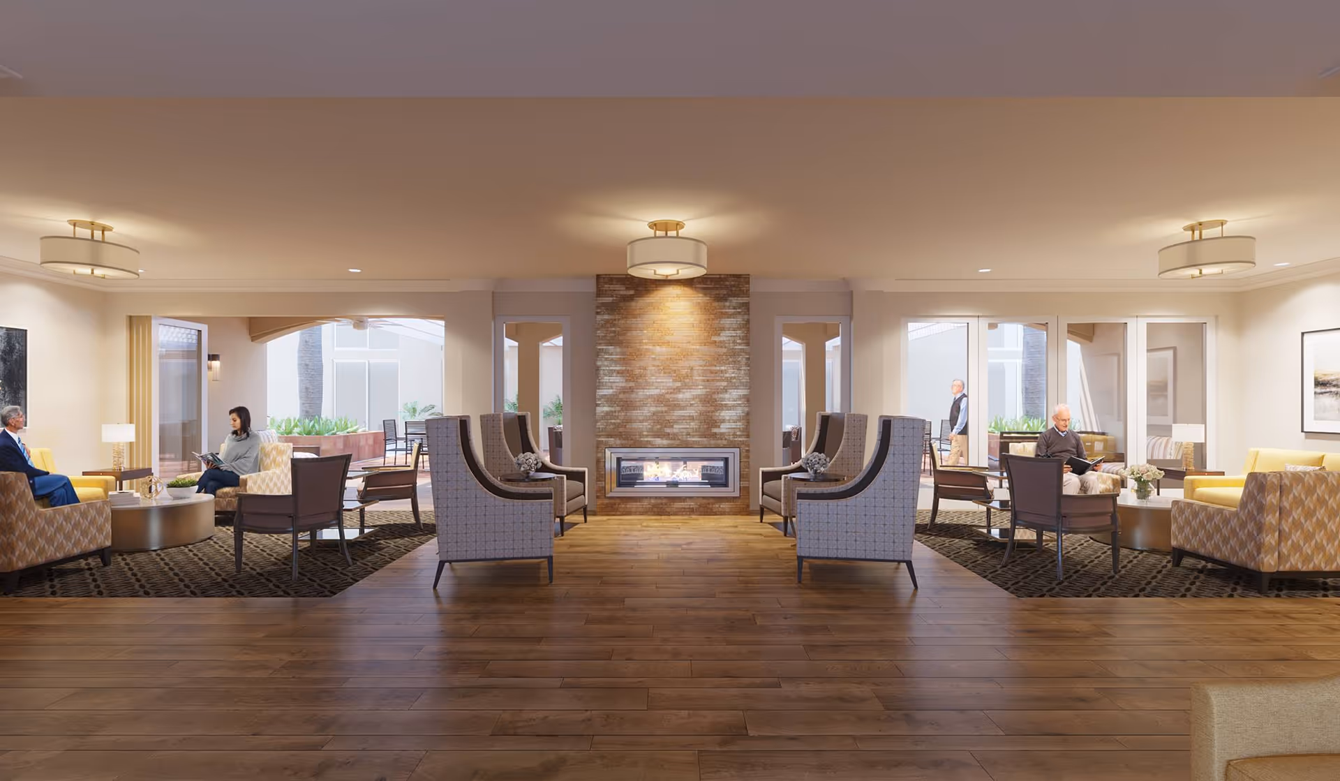 A spacious and well-lit living room area in a senior living facility with wooden flooring, a central modern fireplace with a stone surround, and multiple seating arrangements including armchairs and sofas. Several seniors are seated and engaged in conversation or reading. Large windows and glass doors allow natural light to enter, and there are plants visible outside.