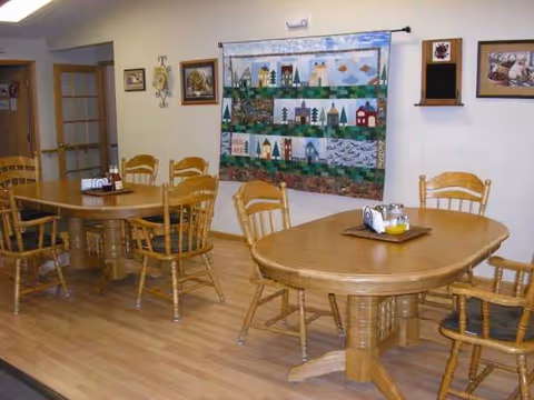Wooden dining tables and chairs in a cozy senior living dining room.