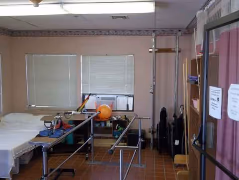 Therapy room in a care center with bed, parallel bars, and equipment.