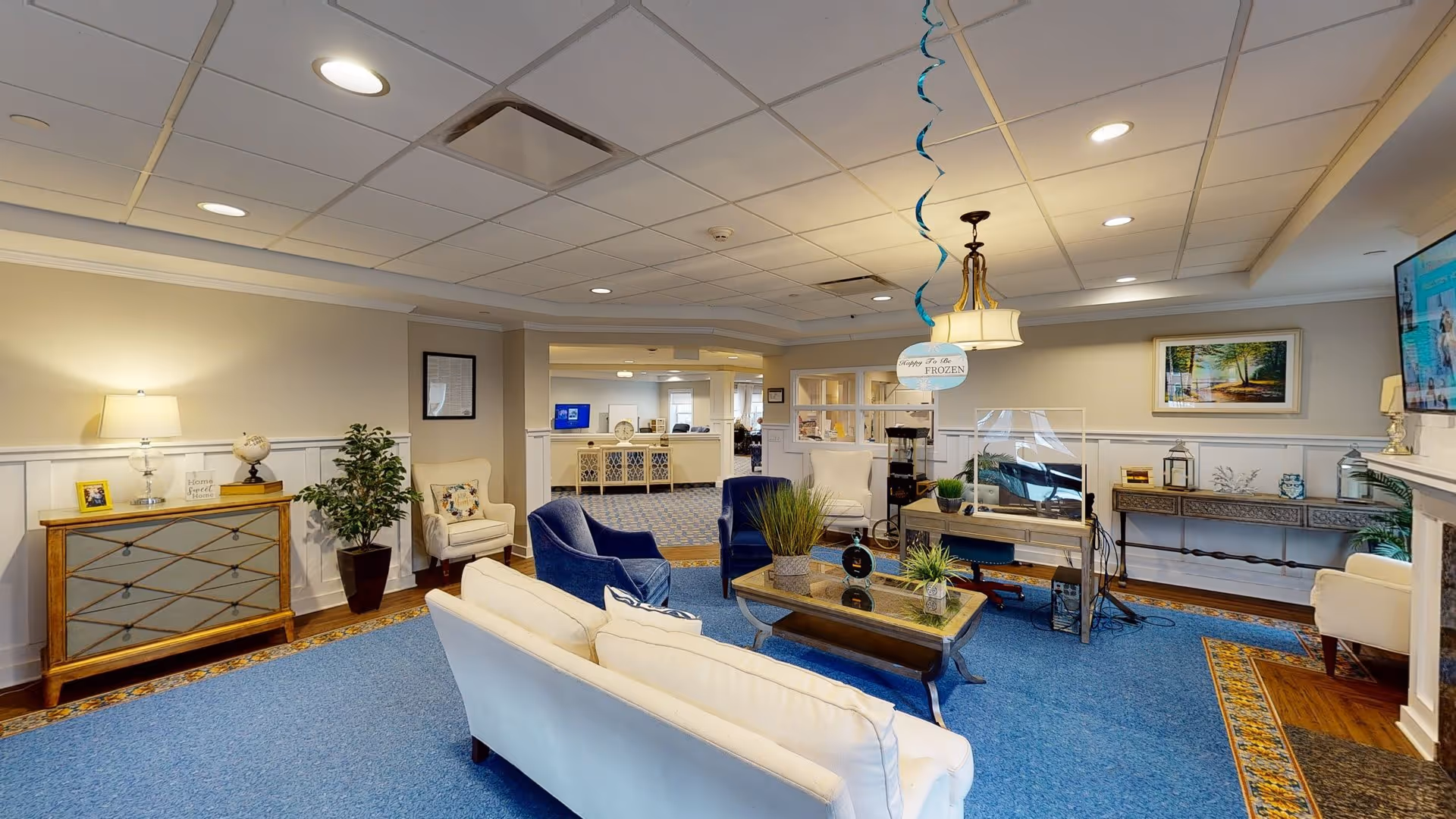 Bright communal living room/lounge with sofas, armchairs, coffee table, TV and decorative accents.