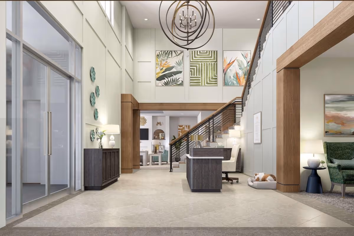 Bright modern lobby with a reception desk, staircase, seating area, and decorative artwork on the walls.