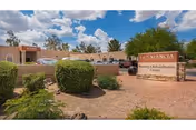 Front exterior of Ahwatukee Post Acute nursing and rehabilitation facility with a stone entrance sign, desert landscaping, and parked cars under a partly cloudy sky.