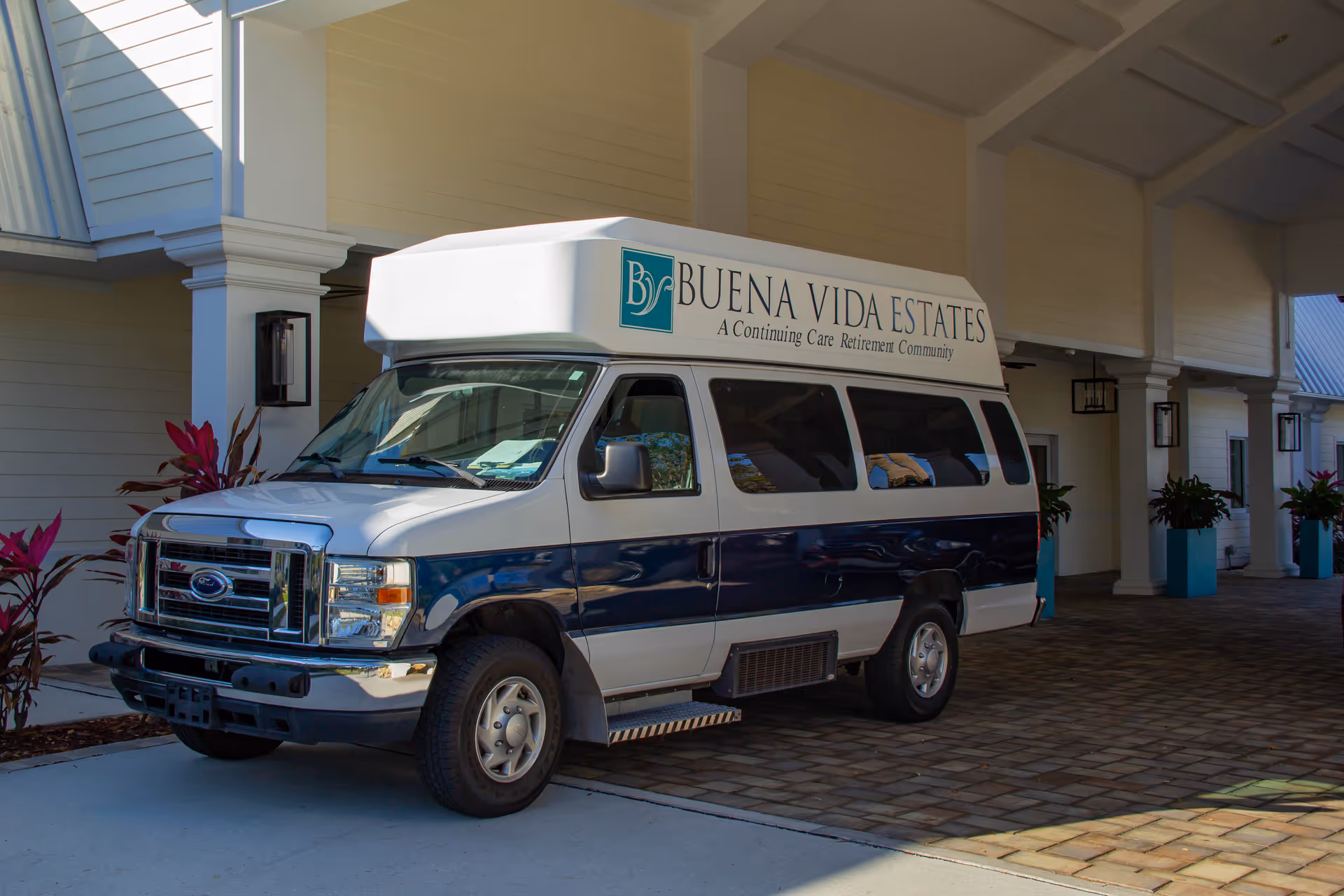 A Buena Vida Estates shuttle van parked under the covered entrance of the retirement community.
