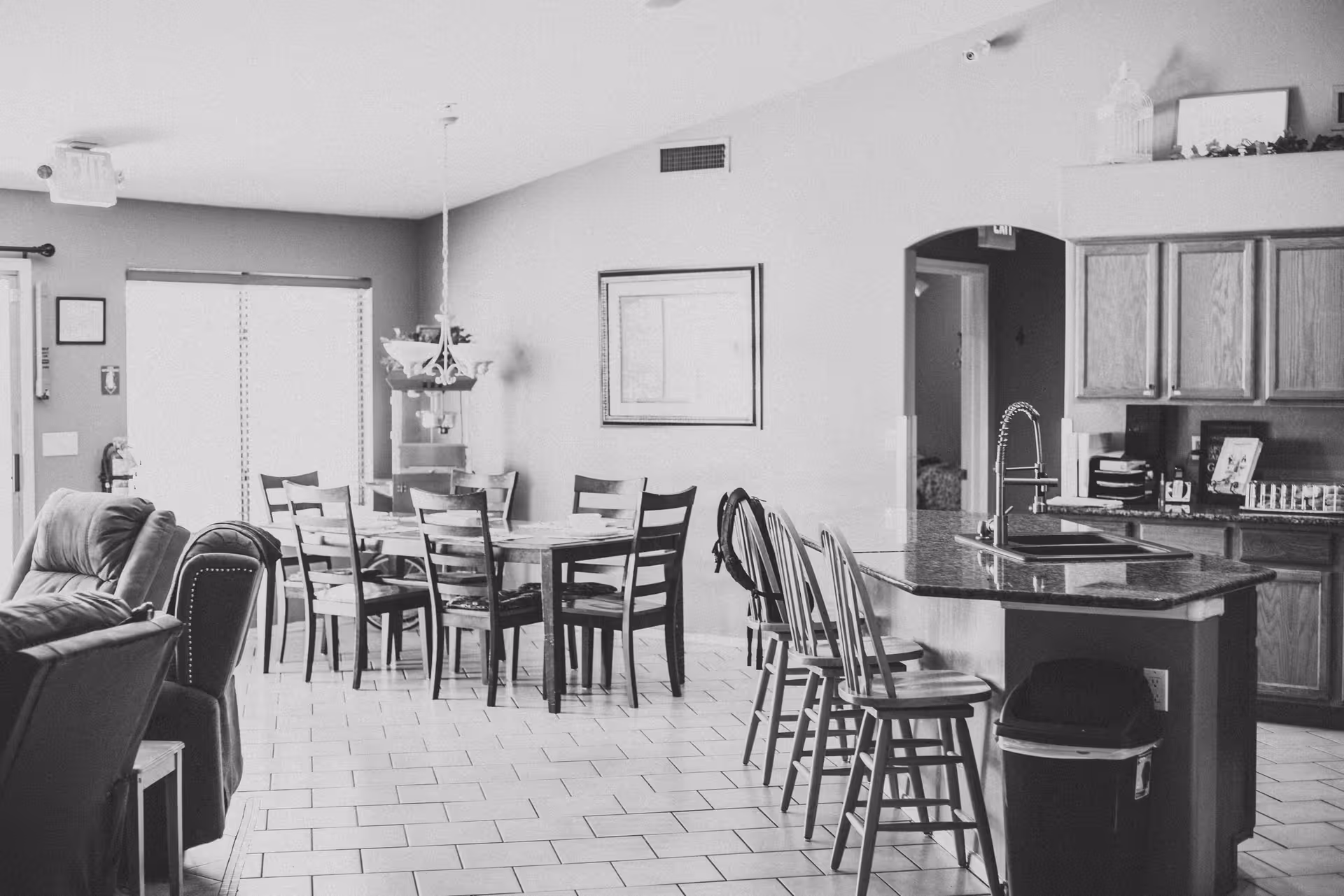 Open-plan interior with a dining table and chairs, a kitchen island with bar stools, and a seating area.