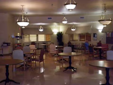 Interior dining room at Sabine Retirement & Rehab Center with round tables and chairs.