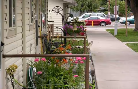 Front exterior of a senior living facility with a flower-filled porch and walkway.