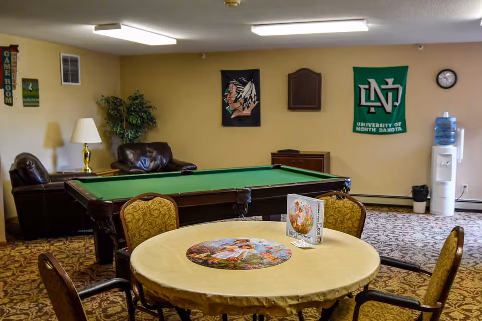 Community game room with a pool table, round table and chairs, lounge seating, and a water cooler.