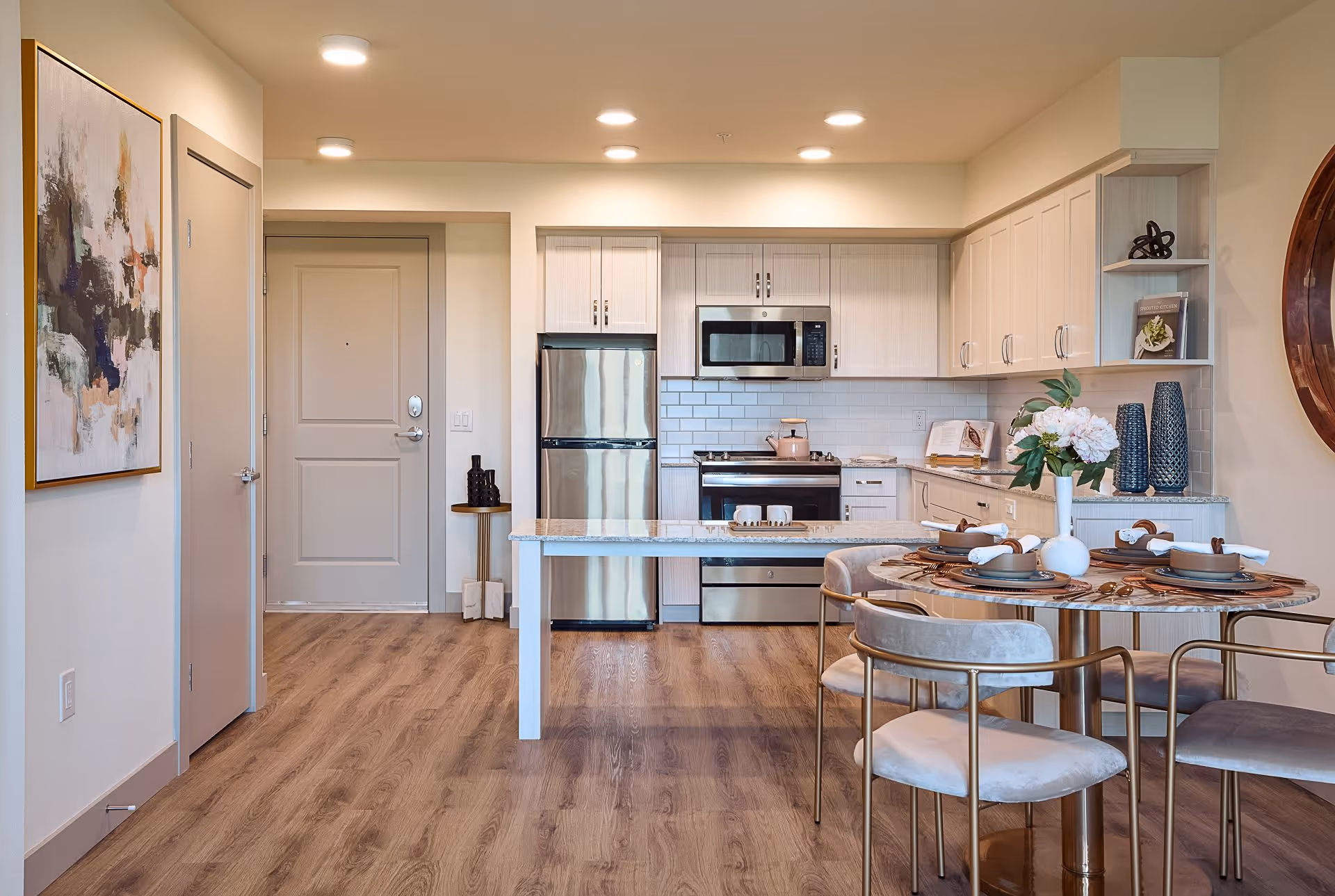Open-concept kitchen and dining area with stainless steel appliances, a marble-topped island, and a set dining table.