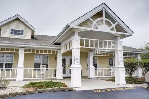 Front exterior view of a light-yellow senior living facility with white columns and porch.