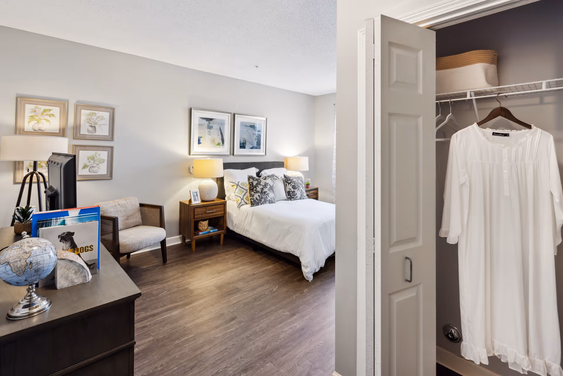 Furnished bedroom with a bed, nightstands, chair, dresser and an open closet showing a hanging white dress.