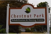 A large outdoor sign for Chestnut Park Rehabilitation & Nursing Center with trees and a building partially visible in the background.