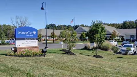 Exterior view of ManorCare Washington Township with front sign, landscaping, and parking.