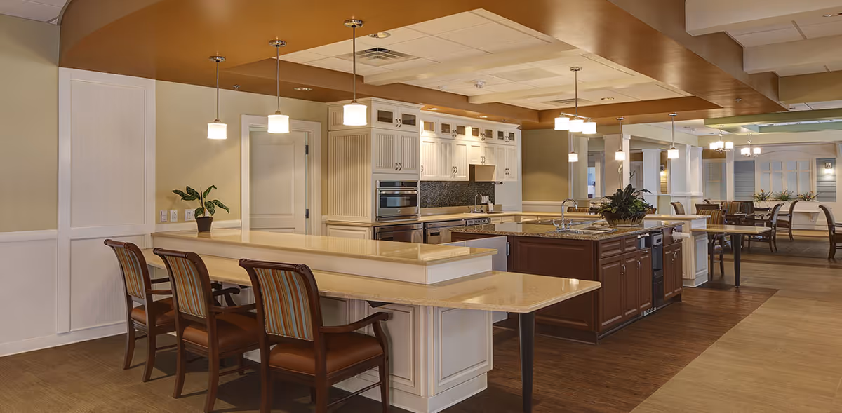 Spacious communal kitchen and dining area featuring a large island with bar seating, pendant lights, and white cabinetry.