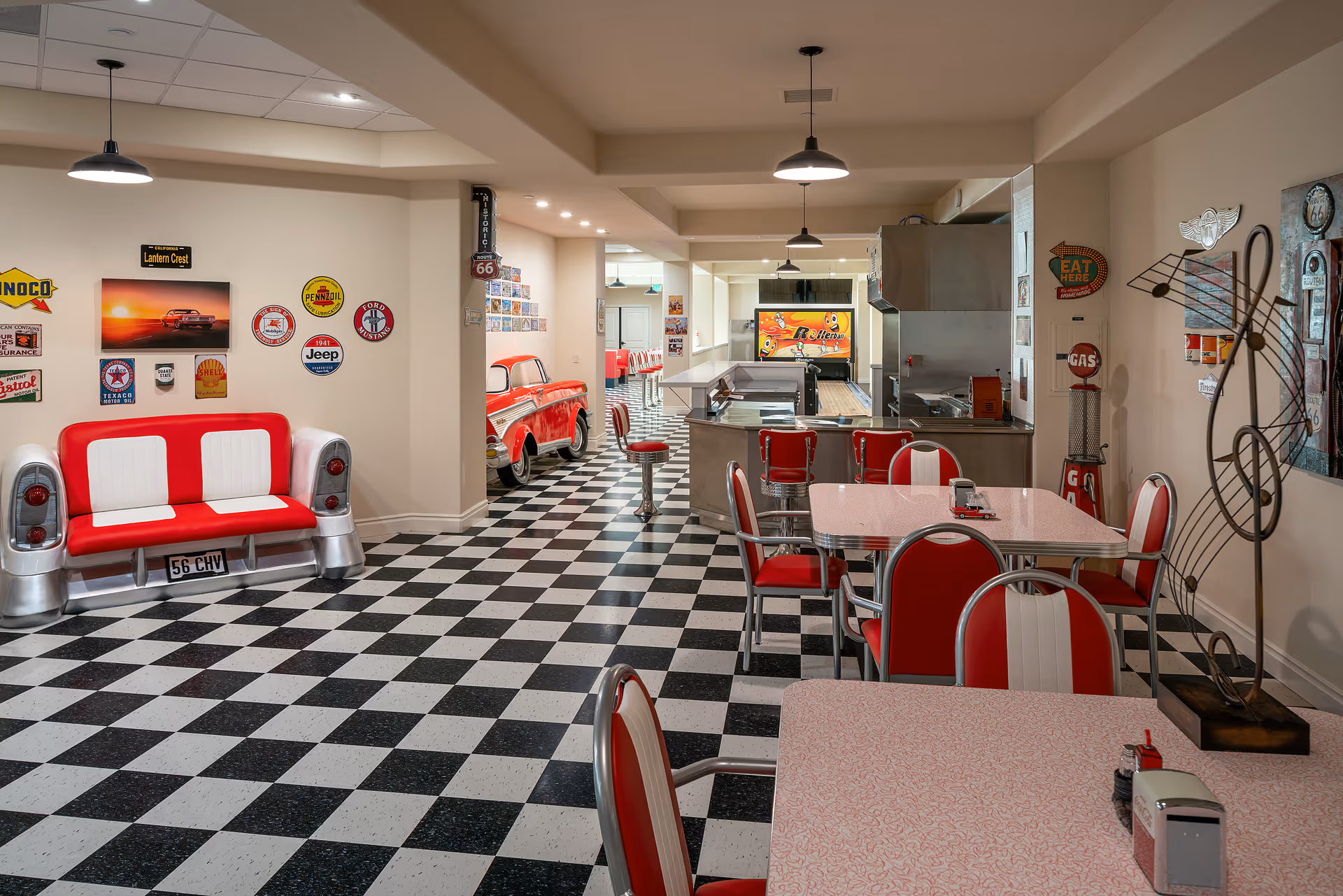 Retro 1950s-style dining area with black-and-white checkered floor, red-and-white diner booths and tables, and a service counter/kitchen.