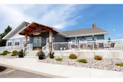 Front exterior of Edgewood Minot senior living facility with porch, railing, and low landscaping.