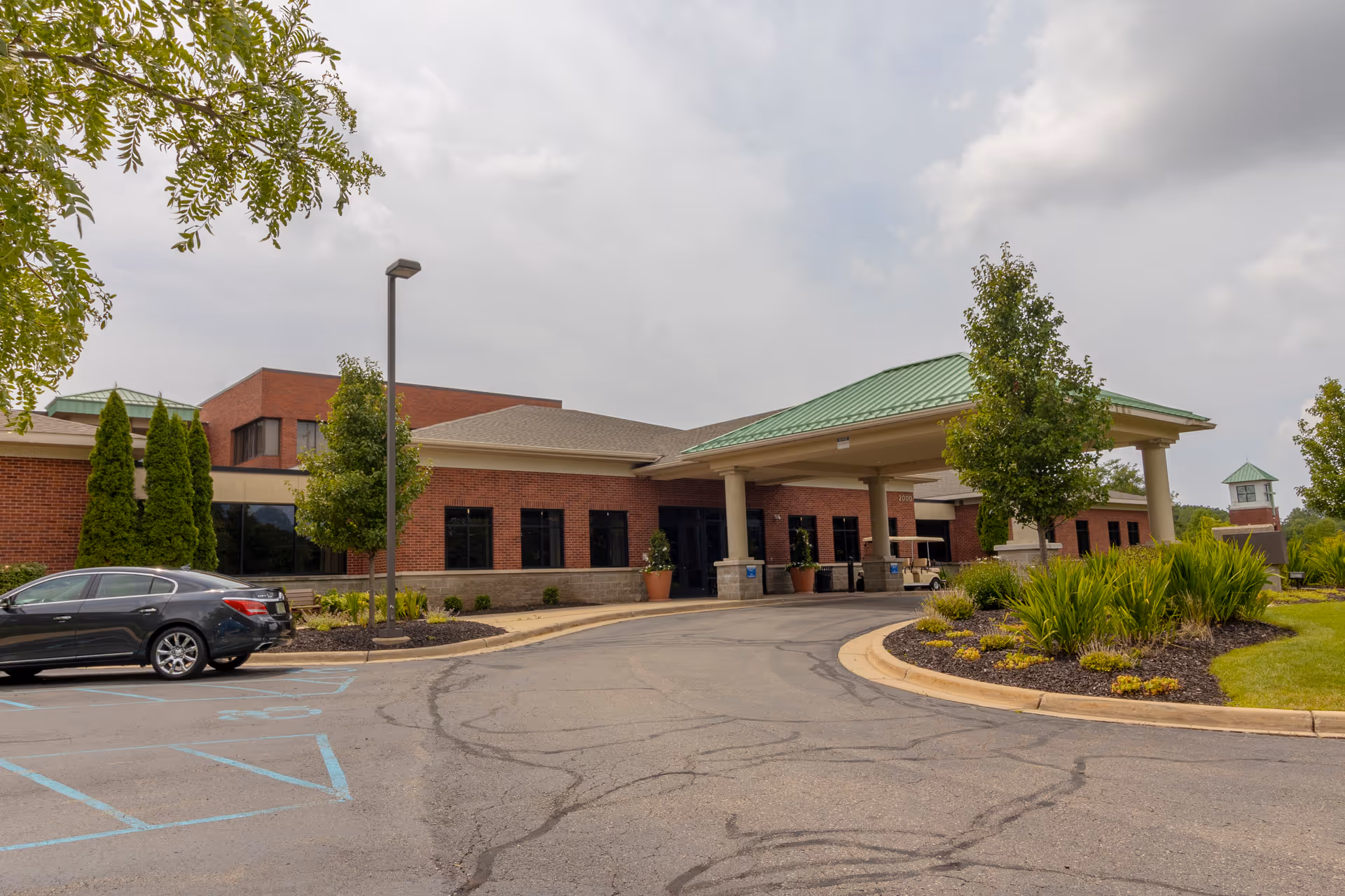 Exterior view of StoryPoint Grand Rapids East, showing entrance, parked car, and landscaped driveway.