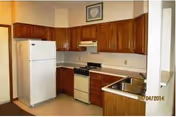 Compact kitchen in a senior living facility with wooden cabinets and white appliances.
