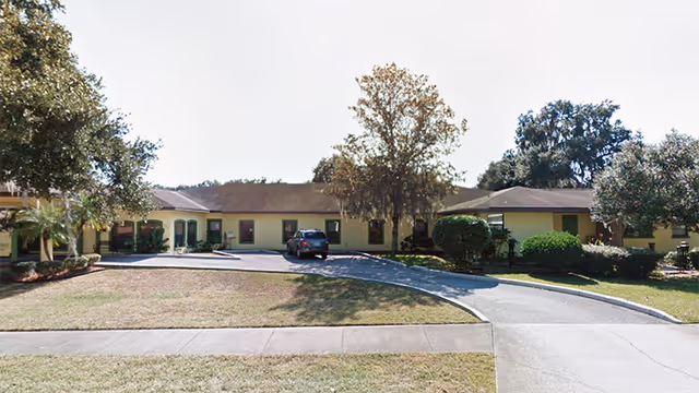 Front exterior view of Lakeland Manor Assisted Living Facility, a single-story building with driveway and cars.