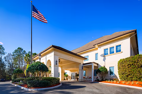 Exterior view of The Windsor of Ocala facility with entrance, flag, and landscaping.