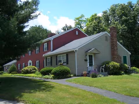 Exterior view of Merriam Village senior living facility with green lawn and walkway