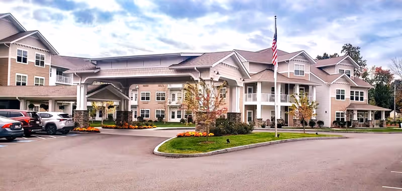 Exterior view of Kennedy Meadows Gracious Retirement Living facility with a porte-cochere and flagpole.