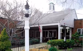 Front view of Cardigan Nursing Home with a covered porch, white columns, and a flag.
