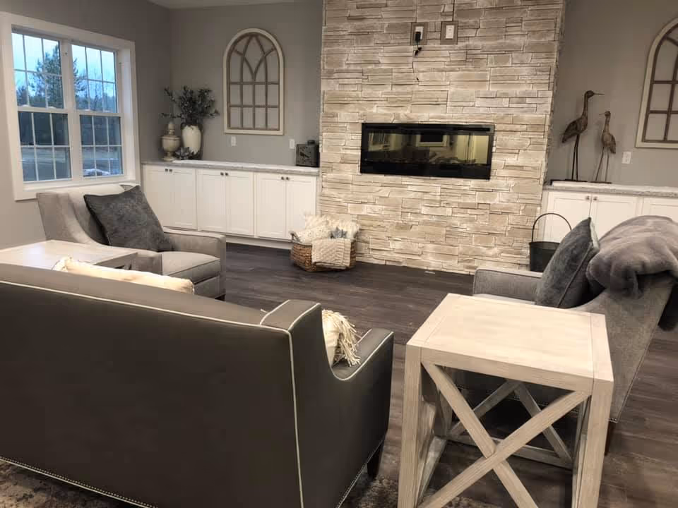 Cozy living room with gray sofas, a stone fireplace, built-in white cabinets and decorative accents.