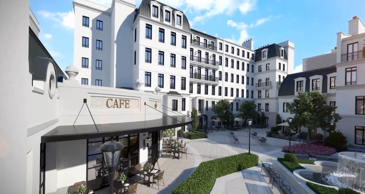 A landscaped courtyard with a café terrace, outdoor seating, a fountain, and surrounding multi-story residential buildings.